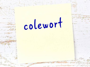 Colewort 'u hatırlatma kavramı. Tahta duvarda üzerinde yazı olan sarı yapışkan kağıt.