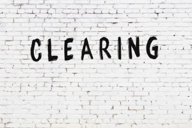 Üzerinde yazı olan beyaz tuğla duvar siyah boyayla el yazısıyla temizleniyor.