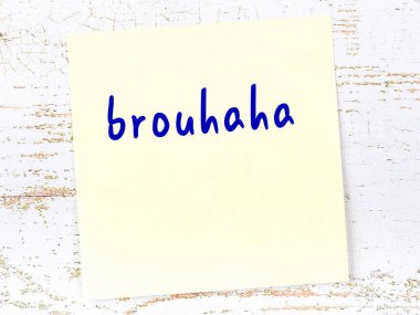 Tahta duvarda el yazısıyla yazılmış sarı yapışkan bir not var.