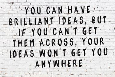 Beyaz tuğla duvara zekice alıntılar yazılı siyah bir yazı.