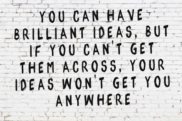 Beyaz tuğla duvara zekice alıntılar yazılı siyah bir yazı.