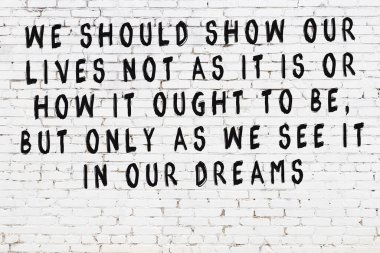 Beyaz tuğla duvar ve bilgece alıntıların yazılı olduğu siyah yazı.