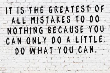 Beyaz tuğla duvara zekice alıntılar yazılı siyah bir yazı.