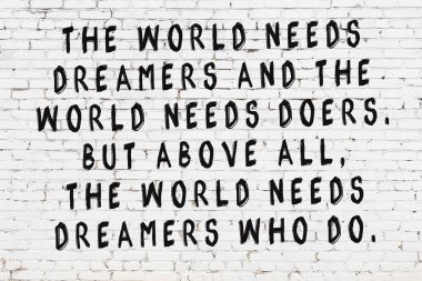 Beyaz tuğla duvara zekice alıntılar yazılı siyah bir yazı.