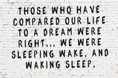 Üzerinde mantıklı alıntıların yazılı olduğu siyah boyanmış beyaz tuğla duvar.