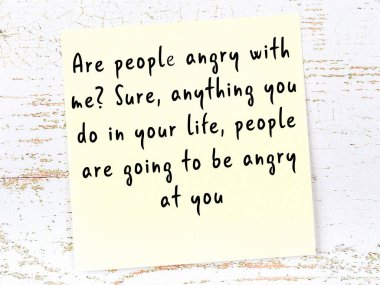 Sarı yapışkan not, ahşap duvarda el yazısıyla yazılmış zekice bir alıntıyla.