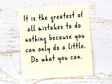 Tahta duvarda el yazısı motivasyon alıntısı olan sarı yapışkan not