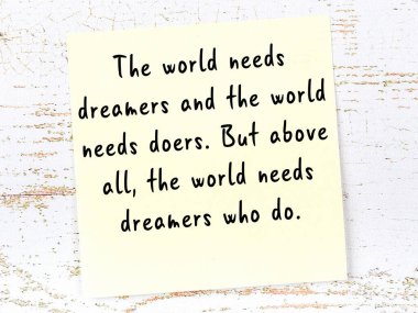 Sarı yapışkan not, ahşap duvarda el yazısıyla yazılmış zekice bir alıntıyla.