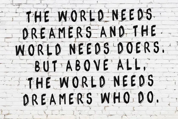 Beyaz tuğla duvara zekice alıntılar yazılı siyah bir yazı.