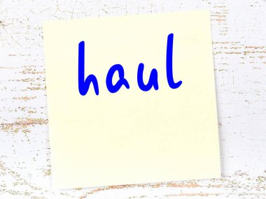 Tahta duvarda el yazısıyla yazılmış sarı yapışkan bir not var.