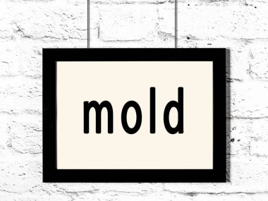 Siyah ahşap çerçeve, beyaz tuğla duvarda yazı kalıbı asılı. 