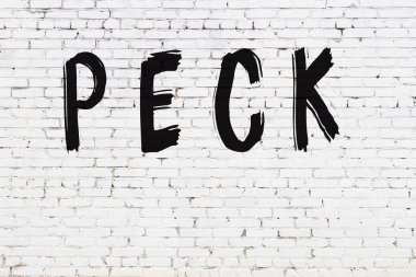 Beyaz tuğla duvara siyah boya ile yazılmış bir gagalama..