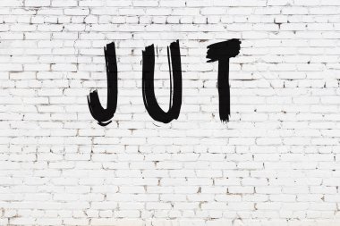 Beyaz tuğla duvara siyah boya ile yazılmış yazma jutu.