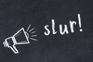 Hoparlörün tebeşir çizimi ve siyah masanın üzerine el yazısıyla yazılmış bir yazı.