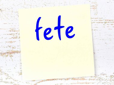 Tahta duvarda el yazısıyla yazılmış sarı yapışkan bir not.