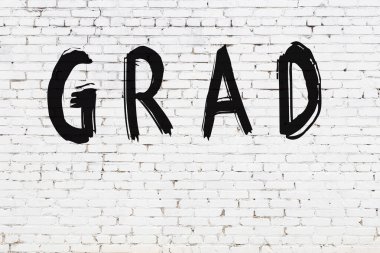 Beyaz tuğlalı duvar, siyah boyayla yazılmış.