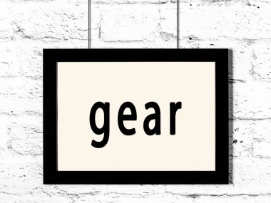 Siyah ahşap çerçeve, beyaz tuğla duvarda yazıt teçhizatı asılı. 