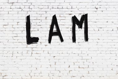 Üzerinde yazı olan beyaz tuğla duvar. Siyah boyayla el yazısıyla yazılmış.