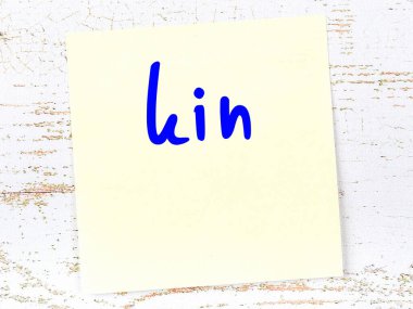 Tahta duvarda el yazısıyla yazılmış sarı yapışkan bir not var.