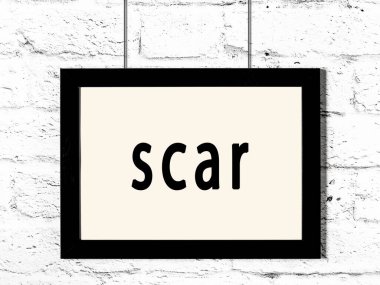 Siyah ahşap çerçeve, beyaz tuğla duvarda yazılı yara izi var. 