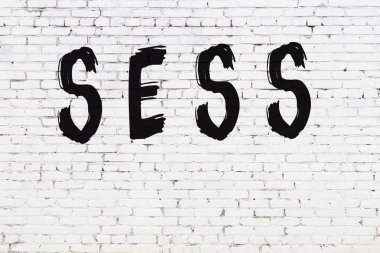 Yazıt değerlendirmesi beyaz tuğla duvarda siyah boya ile yazılmış.