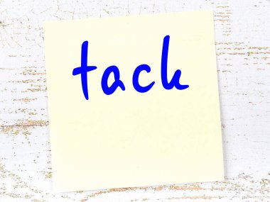 Tahta duvarda el yazısı raptiyeli sarı yapışkan bir not.