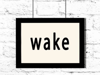 Üzerinde yazı olan siyah ahşap çerçeve beyaz tuğla duvarda asılı. 