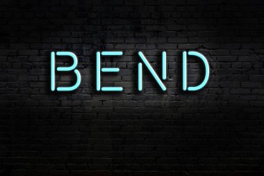 Üzerinde yazı olan neon levhası tuğla duvara yaslanmış. Gece görünümü