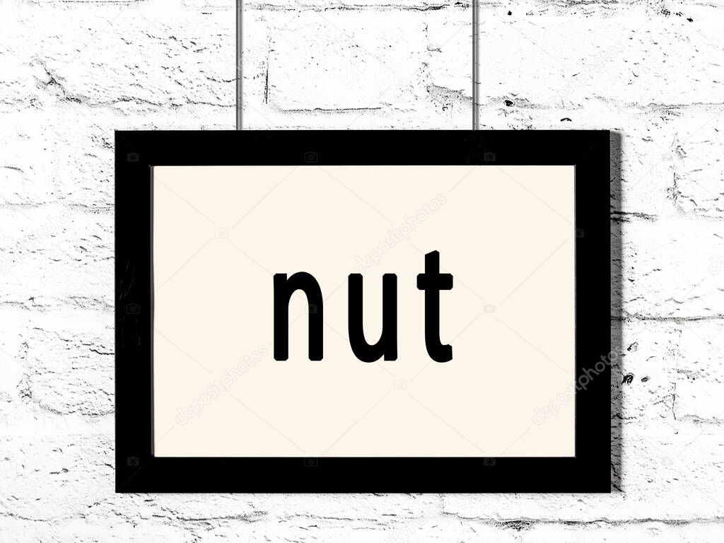 Black wooden frame with inscription nut hanging on white brick wall 