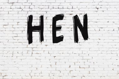 Beyaz tuğlalı duvar. Üzerinde siyah boya yazılı tavuk resmi var.