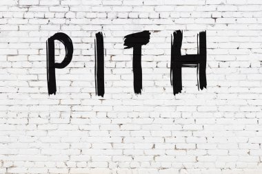 Beyaz tuğla duvarda siyah boyayla yazılmış yazı karakteri.