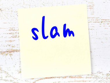 Tahta duvarda el yazısıyla yazılmış sarı yapışkan bir not var.