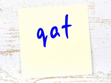 Tahta duvarda el yazısıyla yazılmış sarı yapışkan bir not var.