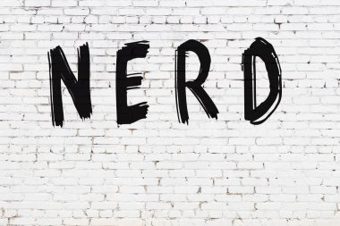 Üzerinde siyah boya ile el yazısı olan beyaz tuğla duvar.