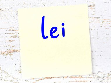 Lei 'yi hatırlatma kavramı. Tahta duvarda üzerinde yazı olan sarı yapışkan kağıt.