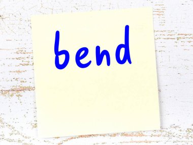 Tahta duvarda el yazısıyla yazılmış sarı yapışkan bir not var.