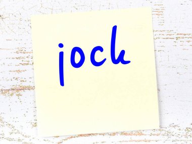 Tahta duvarda el yazısıyla yazılmış sarı yapışkan bir not var.