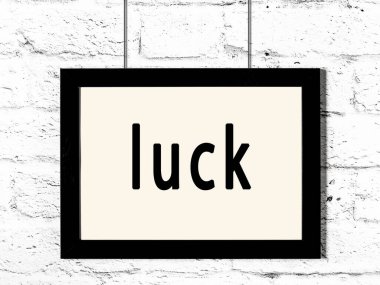 Siyah ahşap çerçeve ve beyaz tuğla duvarda yazılar asılı. 