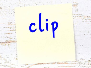 Klipsi hatırlatma kavramı. Tahta duvarda üzerinde yazı olan sarı yapışkan kağıt.