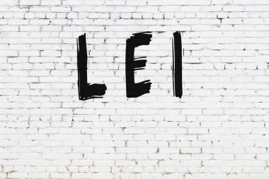 Beyaz tuğla duvara siyah boya ile yazılmış bir lei..