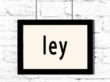 Siyah ahşap çerçeve ve beyaz tuğla duvara kazınmış ley yazısı. 