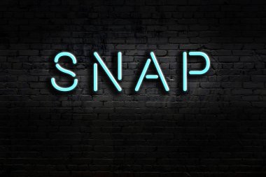Üzerinde yazı olan neon levhası tuğla duvara çarpıyor. Gece görünümü