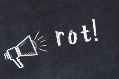 Hoparlörün tebeşir çizimi ve el yazısıyla yazılmış yazı siyah masada çürüyor.