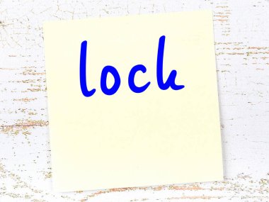 Tahta duvarda, el yazısıyla yazılmış kilidi olan sarı yapışkan not.