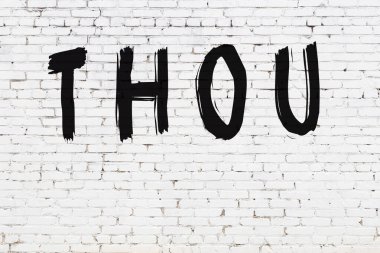 Beyaz tuğla duvara siyah boyayla yazılmış bir yazı..