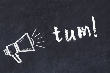 Hoparlörün tebeşir çizimi ve siyah masanın üzerine el yazısıyla yazılmış yazı.