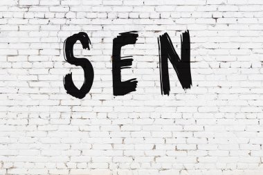 Yazılı beyaz tuğla duvar. Siyah boyayla yazılmış.
