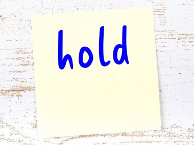 Tahta duvarda el yazısıyla yazılmış sarı yapışkan bir not var.