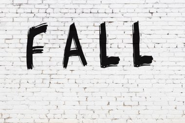 Üzerinde yazı olan beyaz tuğla duvar siyah boyayla el yazısıyla düşmüş.