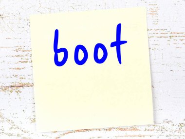 Tahta duvarda, el yazısıyla yazılmış çizmeli sarı yapışkan not.